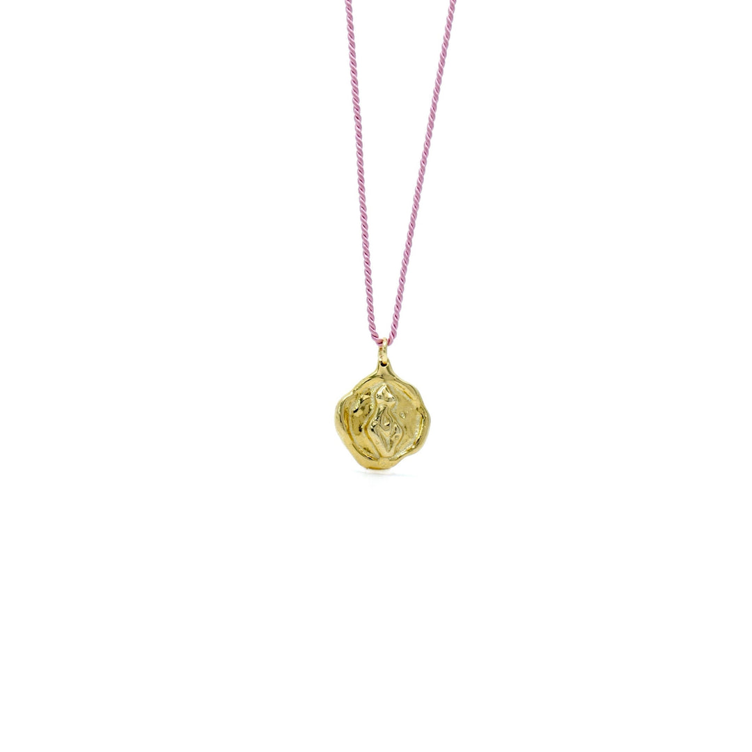 Handcrafted brass Venus coin pendant necklace by Atelier Objectora, with a textured, timeworn aesthetic depicting a female figure on a  pinksilk thread, evoking the essence of ancient artifacts.
Ručne vyrobený mosadzný náhrdelník s medailónom Venuše od Atelier Objectora, s textúrovaným dizajnom a patinovaným vzhľadom, zobrazujúcim ženskú postavu na ružovej hodvábnej šnúrke, pripomínajúci starodávne artefakty.