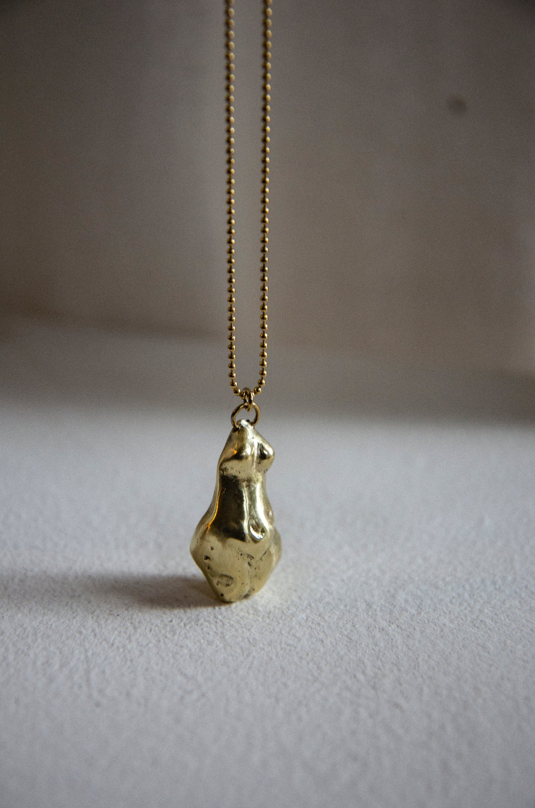 Handcrafted brass Venus pendant necklace by Atelier Objectora, featuring an organic, ancient-inspired design of a female figure on a gold-plated steel chain, embodying raw beauty and feminine strength.
Ručne vyrobený mosadzný náhrdelník s príveskom Venuše od Atelier Objectora, s organickým dizajnom inšpirovaným starovekom, zobrazujúcim ženskú figúru na pozlátenej oceľovej retiazke, vyjadrujúci surovú krásu a ženskú silu.