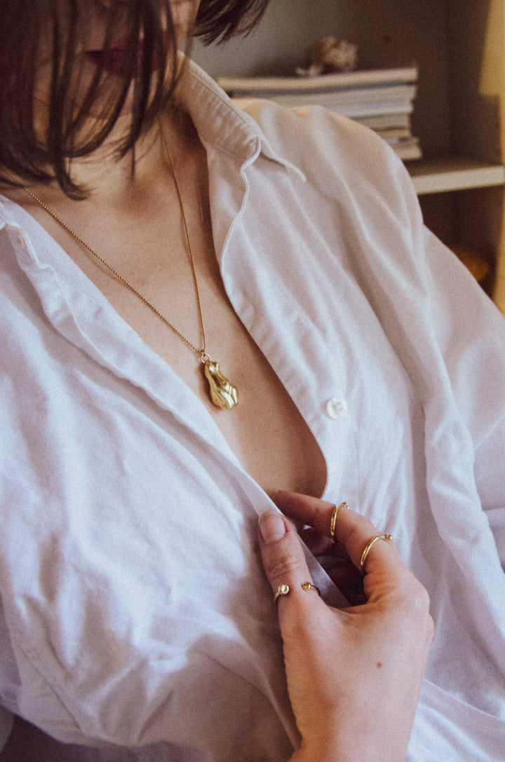 Handcrafted brass Venus pendant necklace by Atelier Objectora, featuring an organic, ancient-inspired design of a female figure on a gold-plated steel chain, embodying raw beauty and feminine strength.
Ručne vyrobený mosadzný náhrdelník s príveskom Venuše od Atelier Objectora, s organickým dizajnom inšpirovaným starovekom, zobrazujúcim ženskú figúru na pozlátenej oceľovej retiazke, vyjadrujúci surovú krásu a ženskú silu.