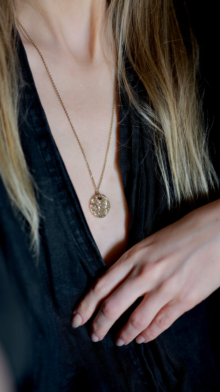 Handcrafted bronze Moonscapes medallion necklace by Atelier Objectora, featuring an organic, molten-textured coin pendant inspired by the moon and the  lunar landscapes. A raw yet elegant statement piece on a sturdy chain.

Ručne vyrobený bronzový náhrdelník Moonscapes od Atelier Objectora s organickým, taveným povrchom medailónu inšpirovaným mesiacom a povrchom mesiaca. Surový, no elegantný šperk na pevnej retiazke.