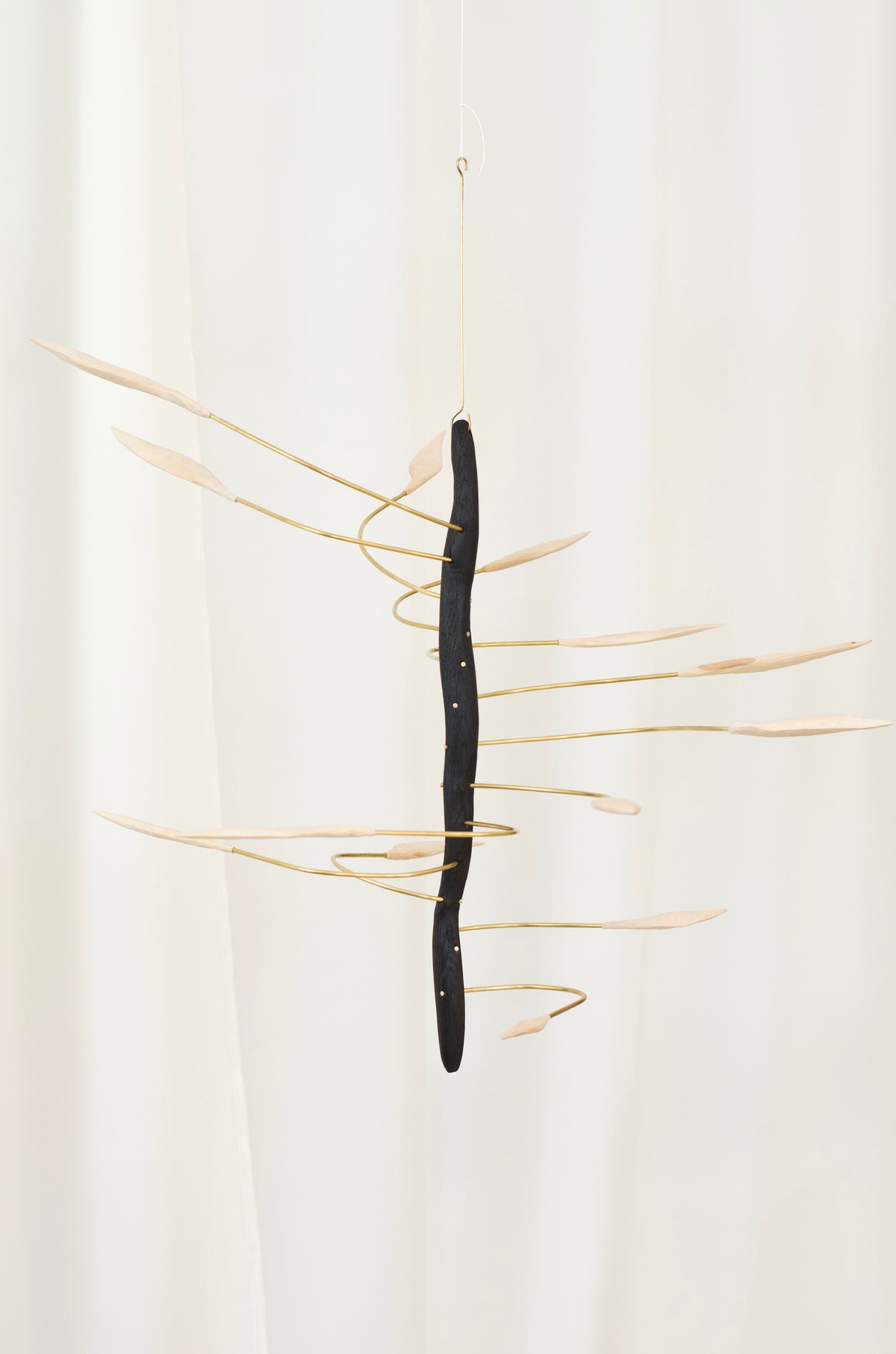 artistic hanging object with a tanned wood base and spiral brass rods on a white background